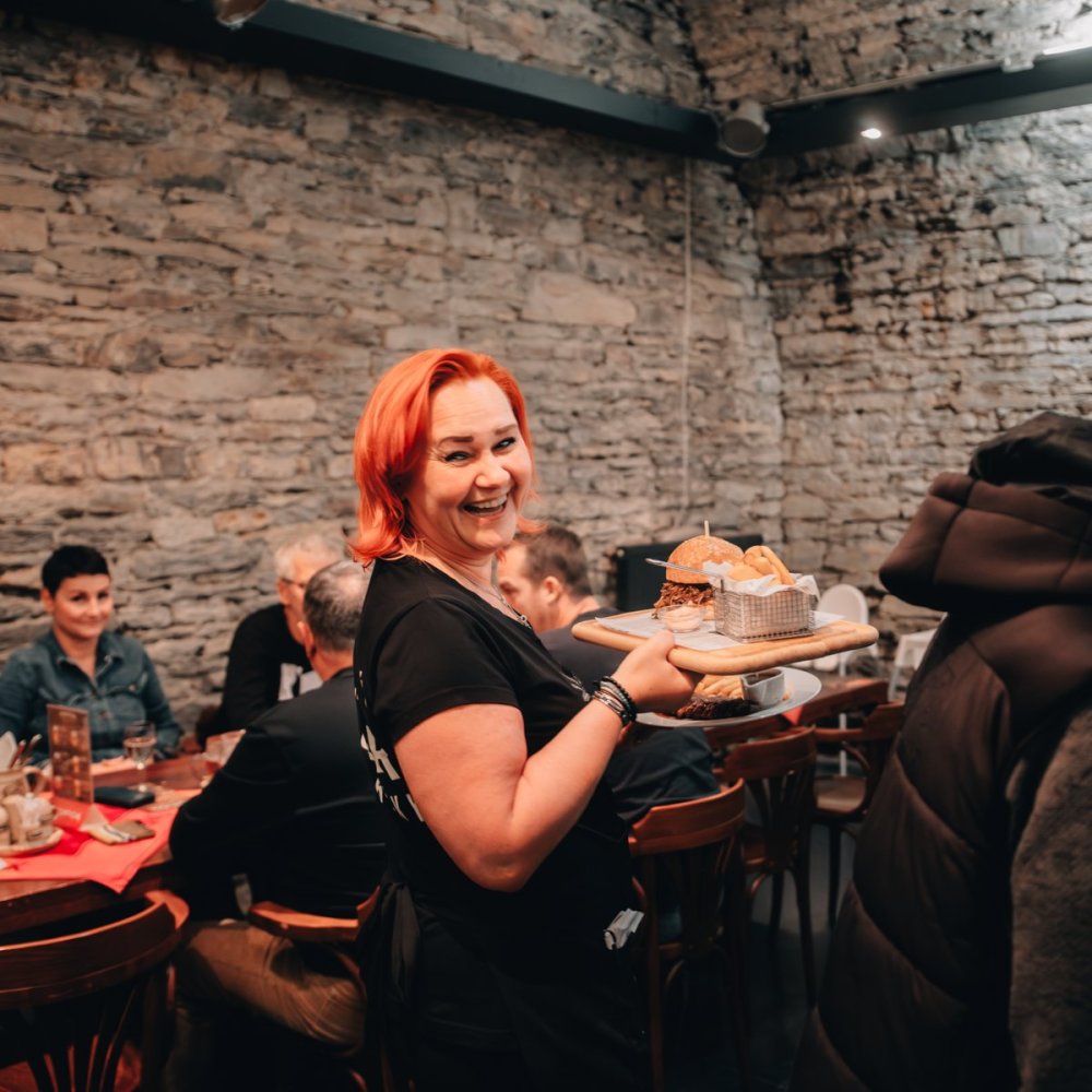 Obsluha ve sklepní restauraci nese jídlo hostům